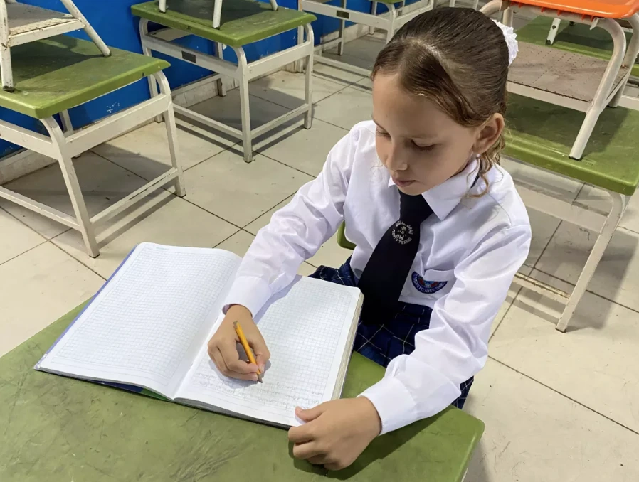 Niña venezolana en colegio de Tumbes haciendo sus tareas (Foto: Unicef)